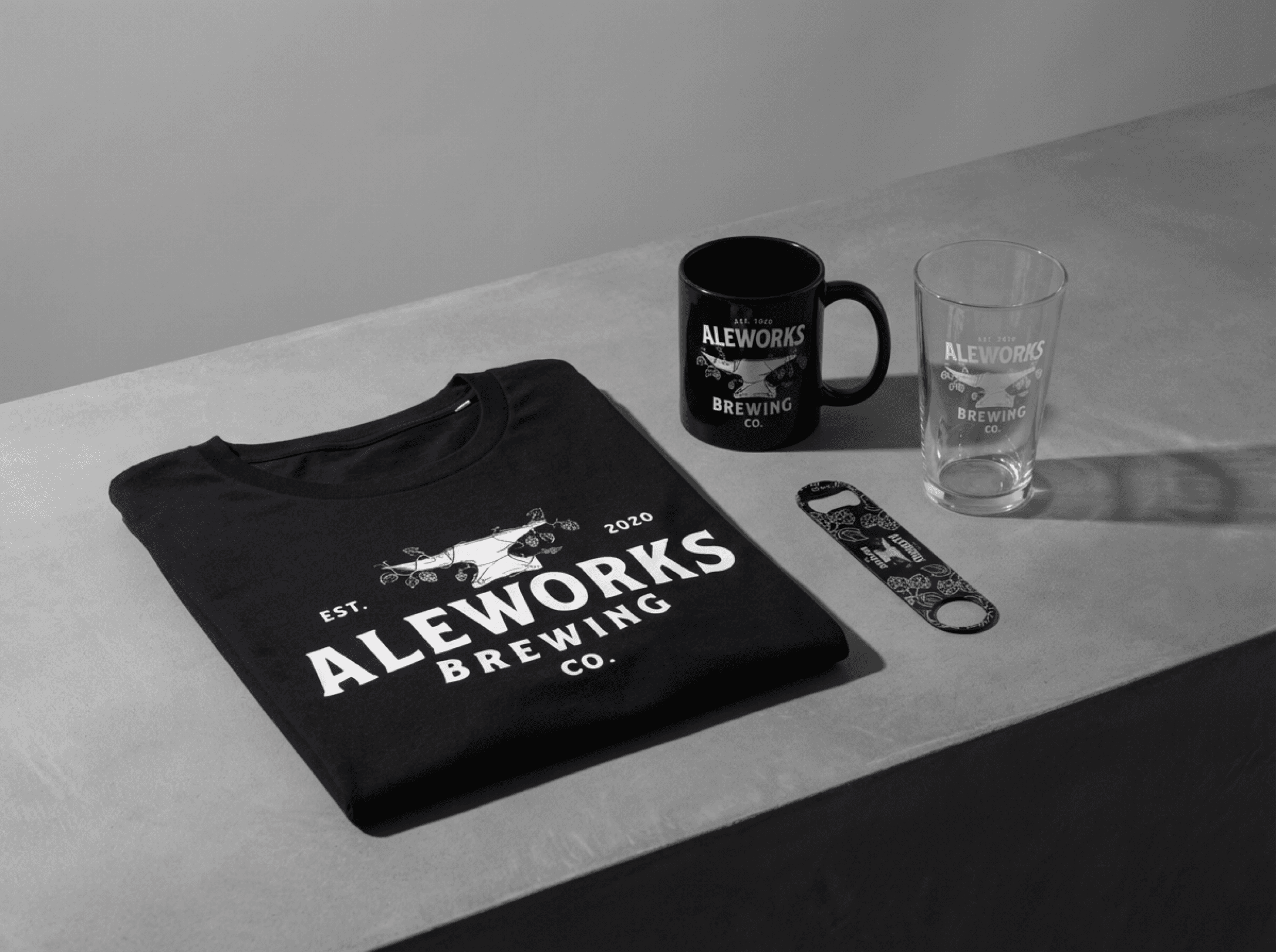 Branded merch flatlay — mug, glassware, opener